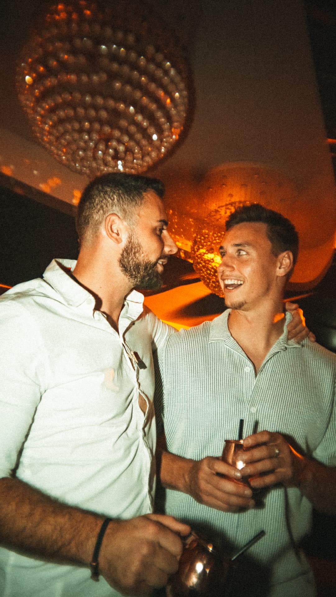 Zwei Freunde mit Drinks unter warmem Licht